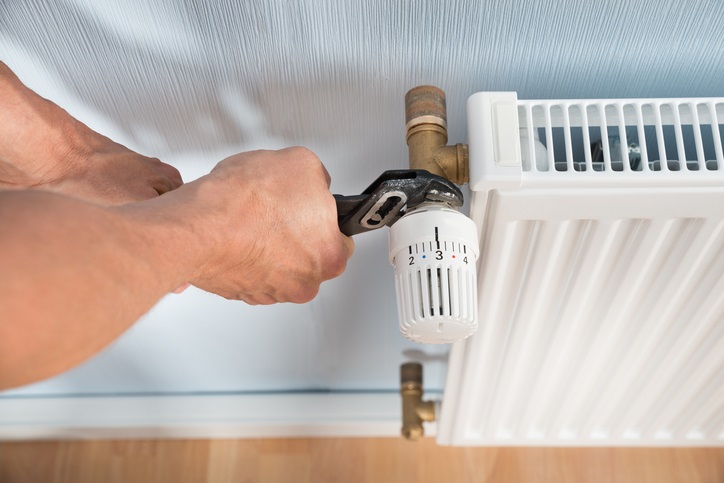Plumber Fixing Radiator With Wrench