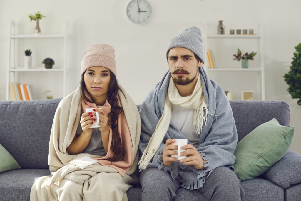 Upset young couple having problem with central heating or suffering from cold home