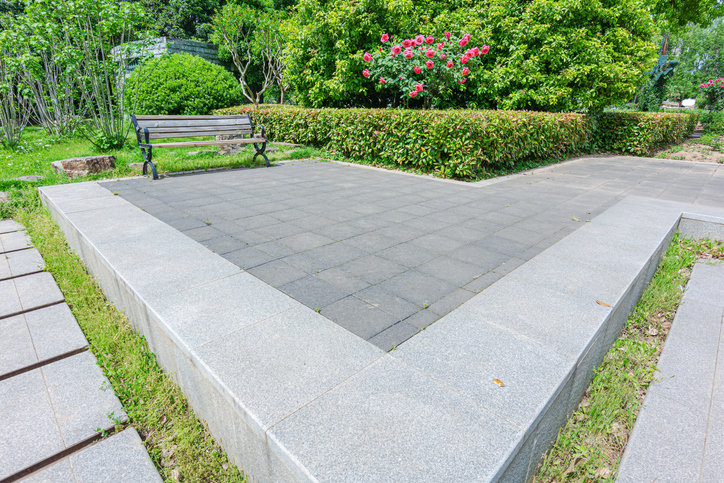 Empty park bench and stone brick pathway in the lush green garden
